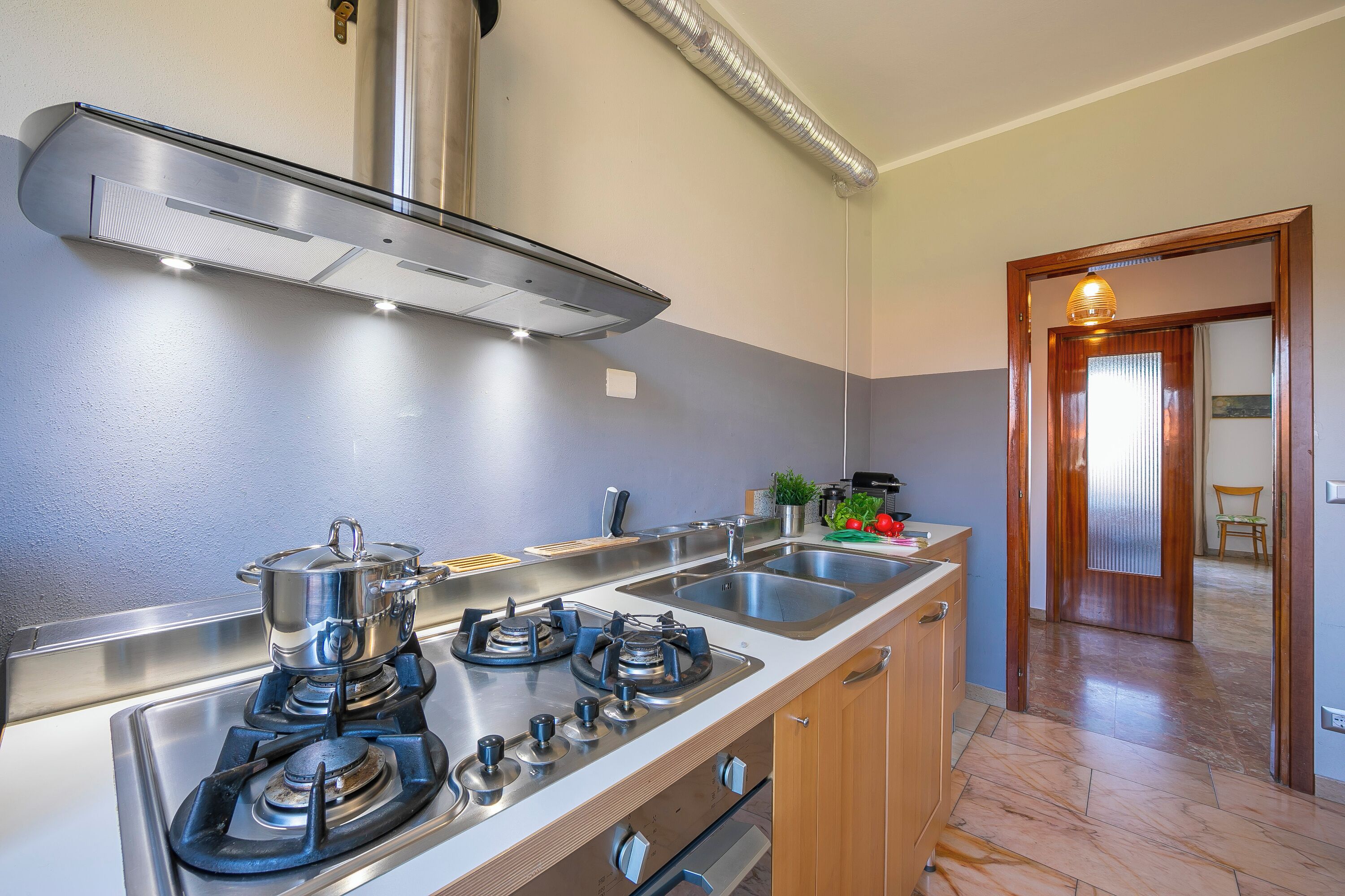 A kitchen with a stove, sink, and stainless steel cabinets.