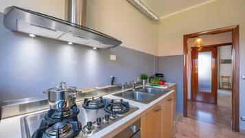 A kitchen with a stove, sink, and stainless steel cabinets.