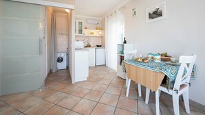Cocina compacta con comedor, lavadora y un refrigerador pequeño.