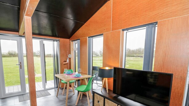 Un salon moderne avec un téléviseur, des meubles en bois et un coin repas comprenant des chaises et une table.