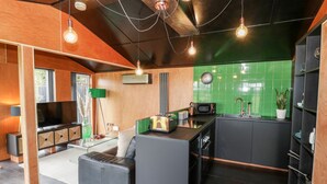 Une cuisine moderne avec un revêtement mural vert, un four encastré et un coin repas comprenant un canapé et un téléviseur.