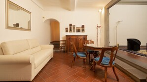 Una sala de estar con sofá, mesa de comedor, sillas, un espejo y chimenea.