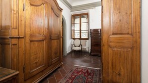 Una habitación con armarios de madera, una silla, una mesita y una ventana.