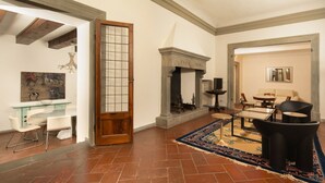 Una amplia sala de estar con chimenea, un comedor con mesa de vidrio y una zona de estar con sillas modernas.