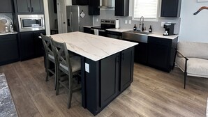 Una cocina moderna con armarios oscuros, una isla central y un comedor.