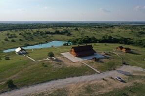 Vue aérienne d’une propriété rurale avec une grande grange, une petite maison et un étang.