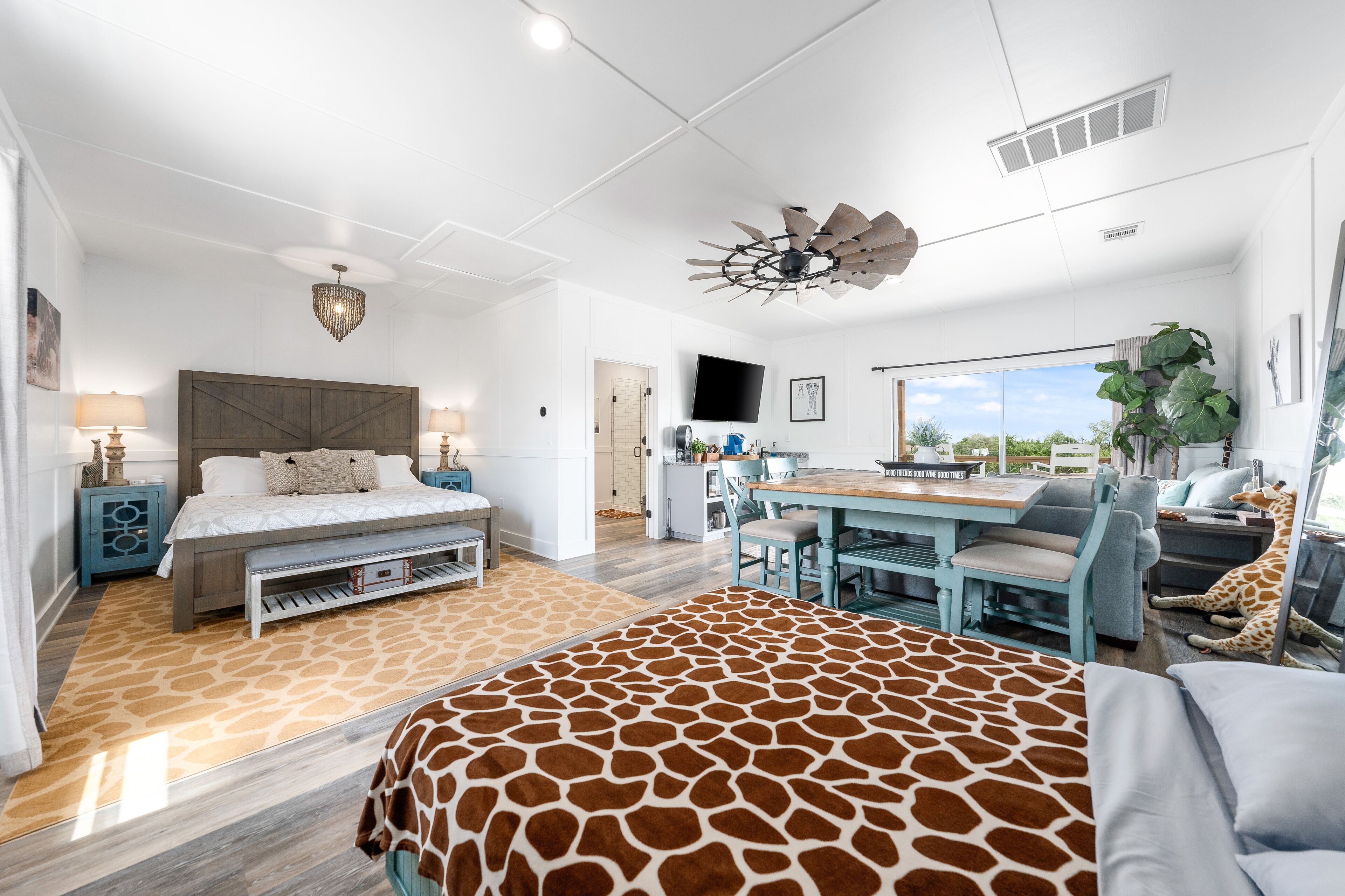 A modern bedroom with a large bed, a desk, and a giraffe statue.