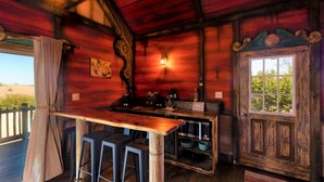 Cocina rústica con barra de madera, taburetes y un ventanal.