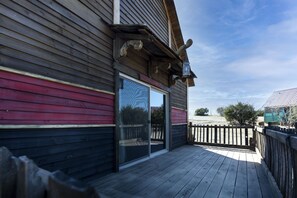 A wooden deck with a glass door leading to a covered outdoor area.