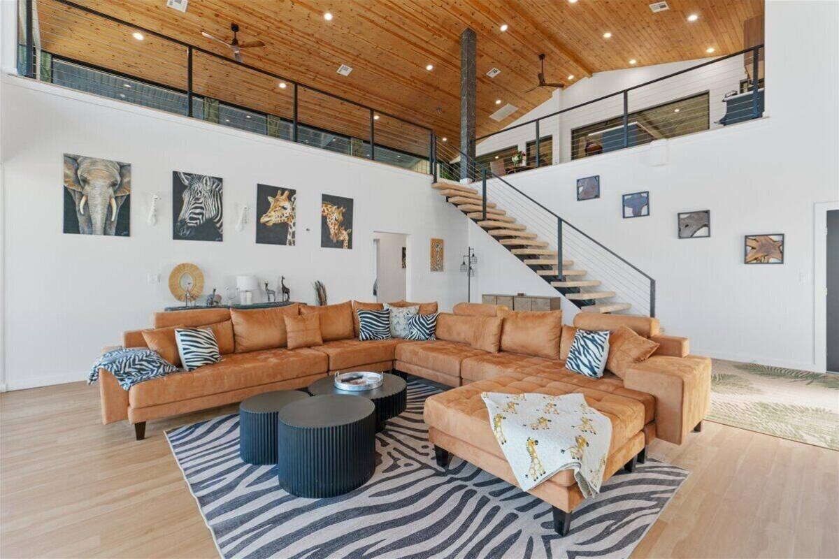 A spacious living area with a large L-shaped sofa, a zebra-patterned rug, and a staircase with a wooden interior.