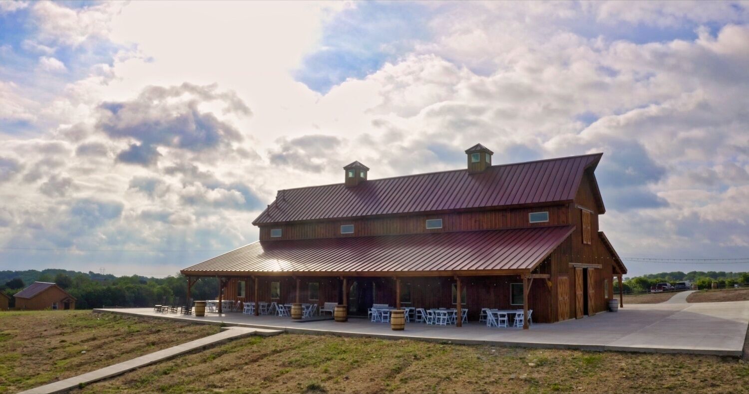 A large wooden barn-style building with a covered patio area and outdoor seating.