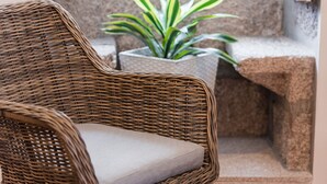 Una silla de mimbre con cojín en un rincón.