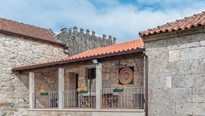 Un edificio de piedra con techo de tejas y un balcón con mobiliario exterior.