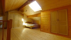 A wooden room with a bed, a wardrobe, and a ceiling fan. - Les hauts de Saint Christaud: large gite overlooking the Pyrenees (Saint-Christaud)