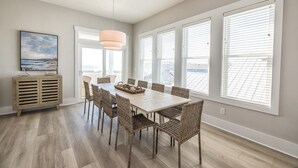 Un espace repas avec une grande table, des chaises en osier et un luminaire suspendu.