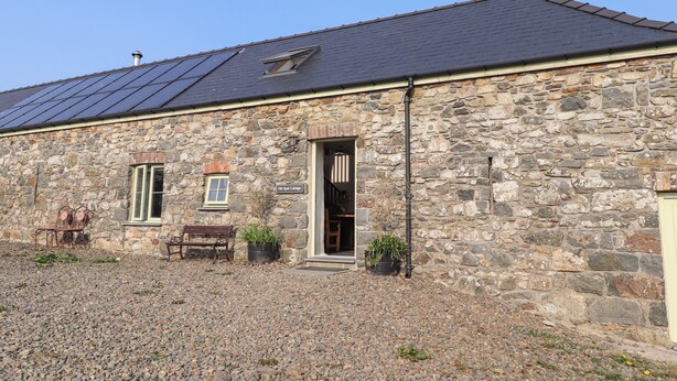 A stone cottage with a sloped roof, a small window, and a door.