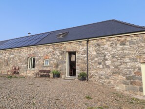 A stone cottage with a sloped roof, a small window, and a door. - Old Spot Cottage (Goodwick)