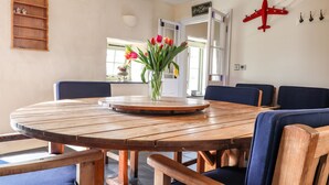 A round wooden table with a central vase of flowers, surrounded by blue upholstered chairs.