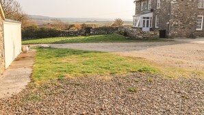 A stone house with a gravel driveway and a grassy area in front.