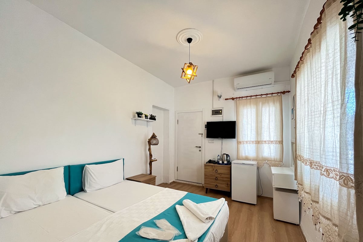 Ein Hotelzimmer mit Bett, Schreibtisch, Fernseher und Klimaanlage.