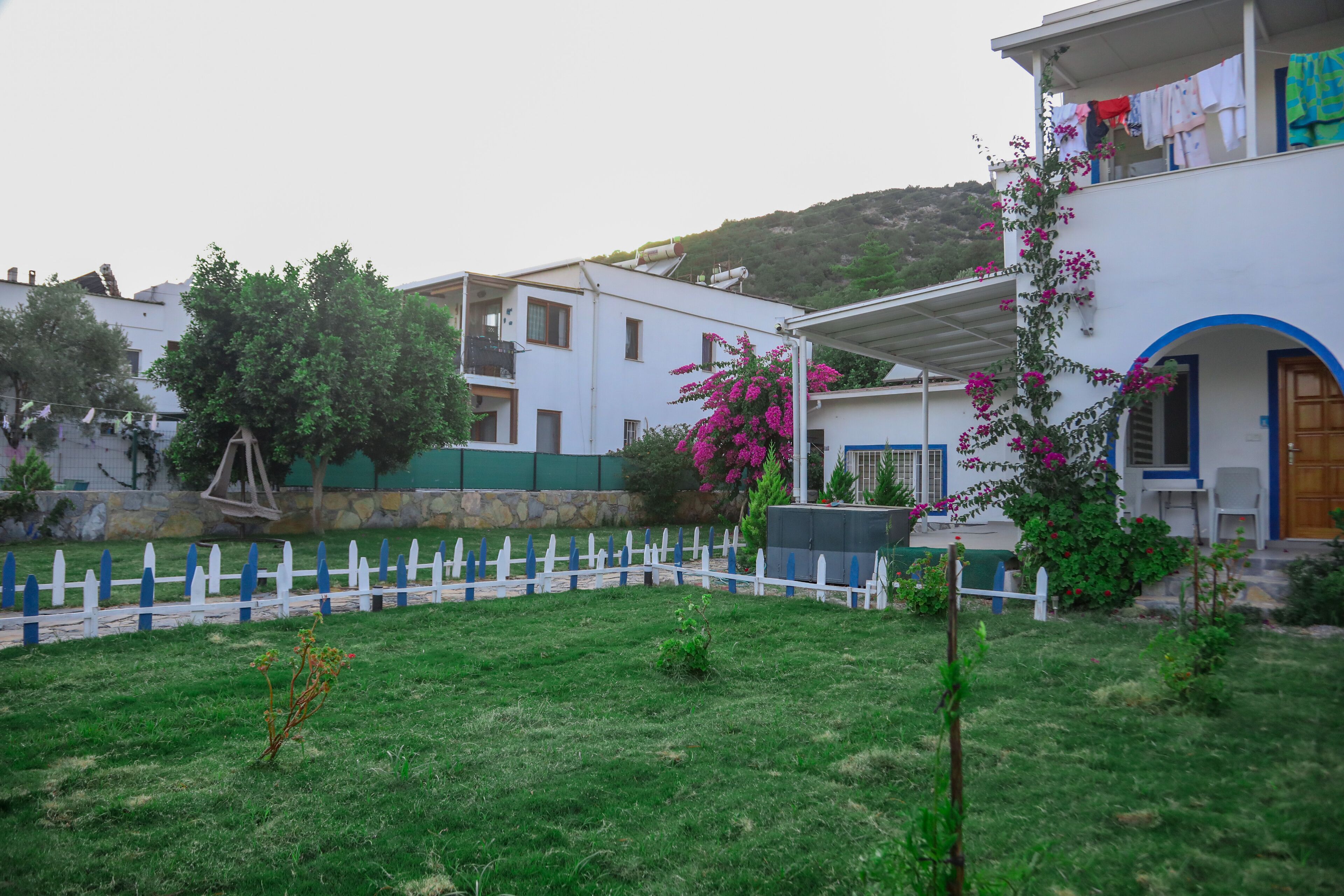 Un barrio residencial con un edificio blanco, un patio cercado y un balcón con ropa tendida.