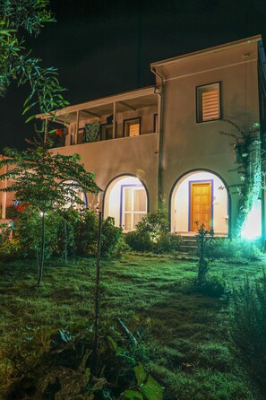 Una casa de dos pisos con un jardín cuidado y una puerta visible con marco azul.