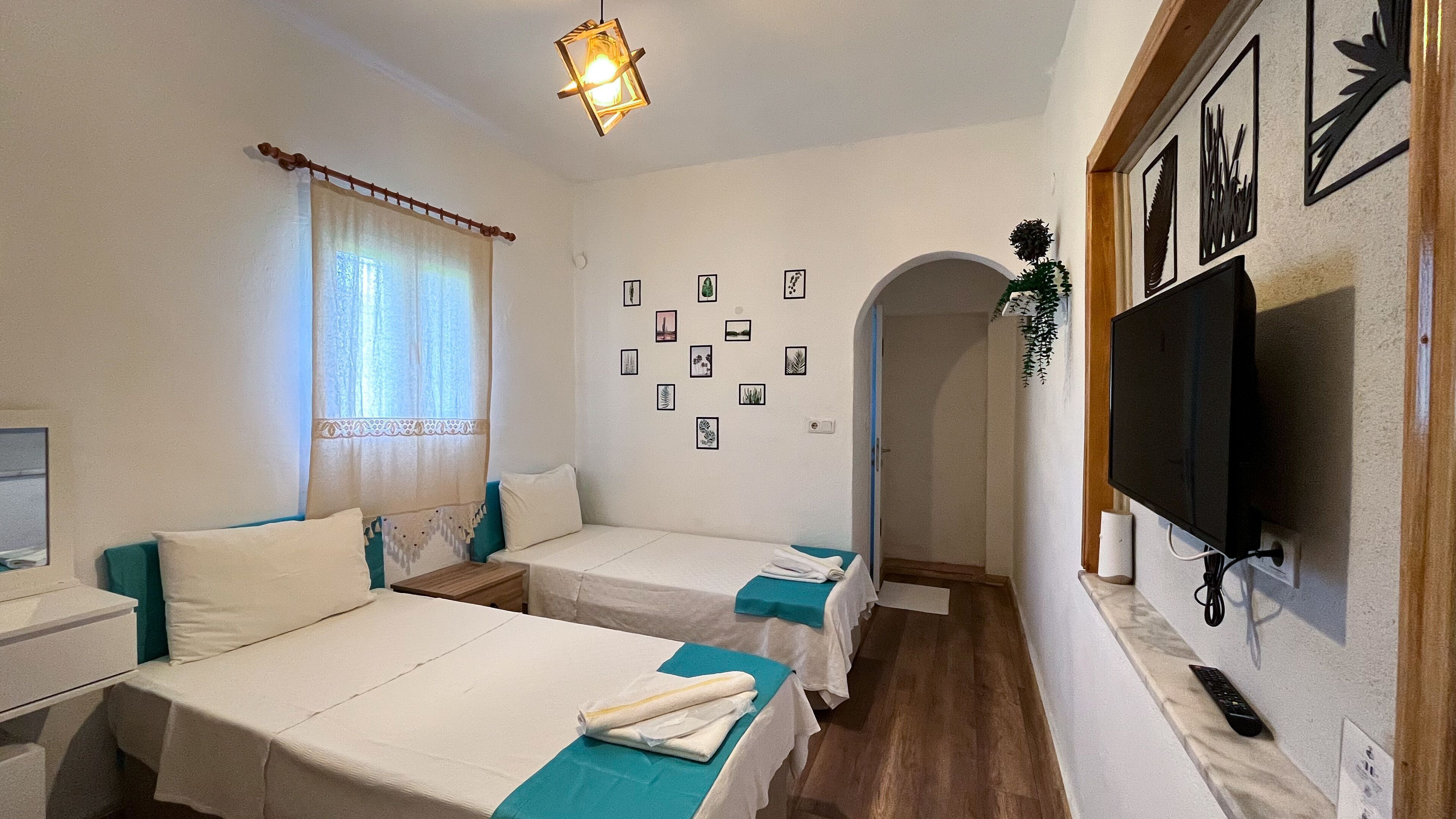 Una habitación con dos camas, un televisor y una pared decorada con cuadros.