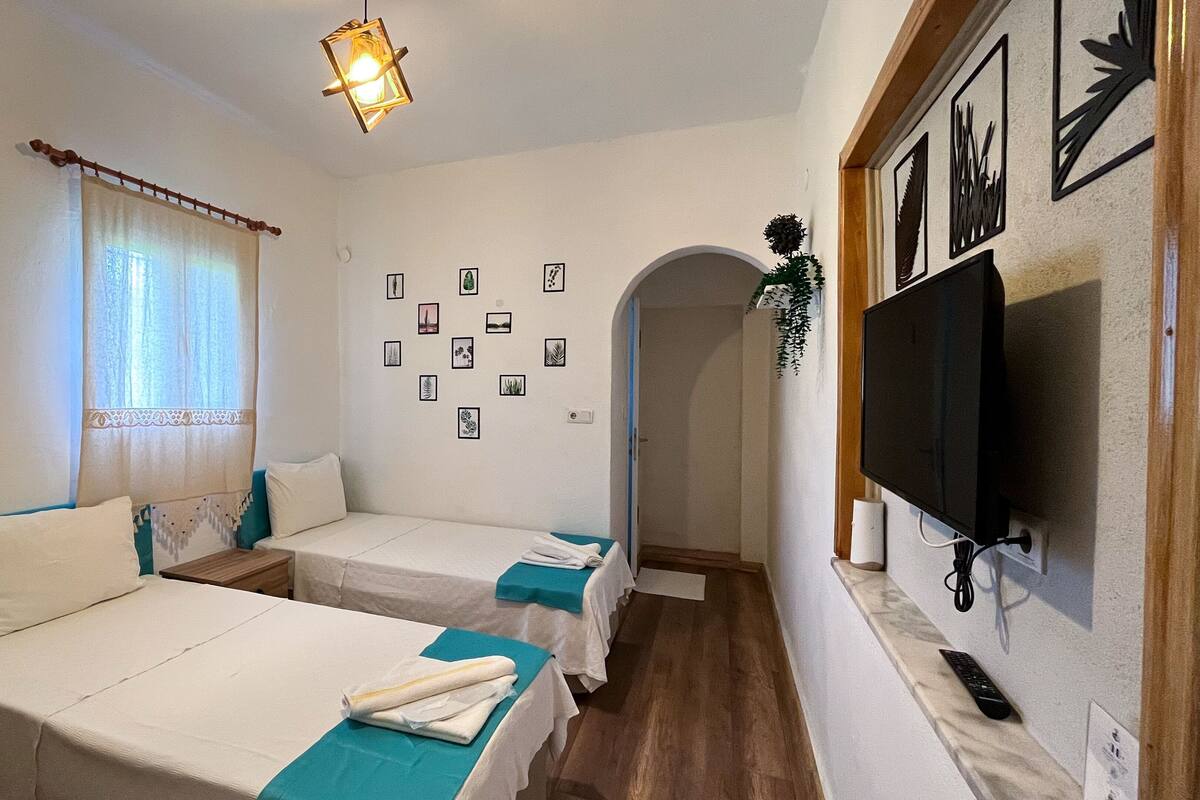 Ein Zimmer mit zwei Betten, einem Fernseher und einer Wand mit gerahmten Bildern.