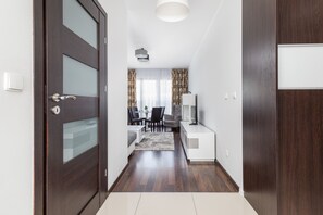 Un pasillo con una puerta de madera, una zona de comedor con mesa y sillas, y un armario blanco.