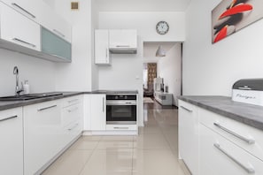 A modern kitchen with white cabinetry, a built-in oven, and a countertop with a sink.