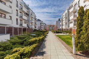 A residential building with multiple balconies, a paved walkway, and well-maintained greenery.