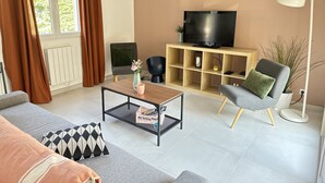 Un salon moderne comprenant un canapé, un fauteuil, une table basse, un meuble pour la télévision et une lampe.