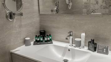 A modern bathroom with a large sink, a mirror, and toiletries.