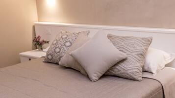 Una cama bien hecha con almohadas estampadas y una mesita de noche con un florero.