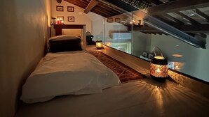 Une chambre confortable avec un lit, une table de chevet, une lampe et une vue sur l’extérieur par une fenêtre.