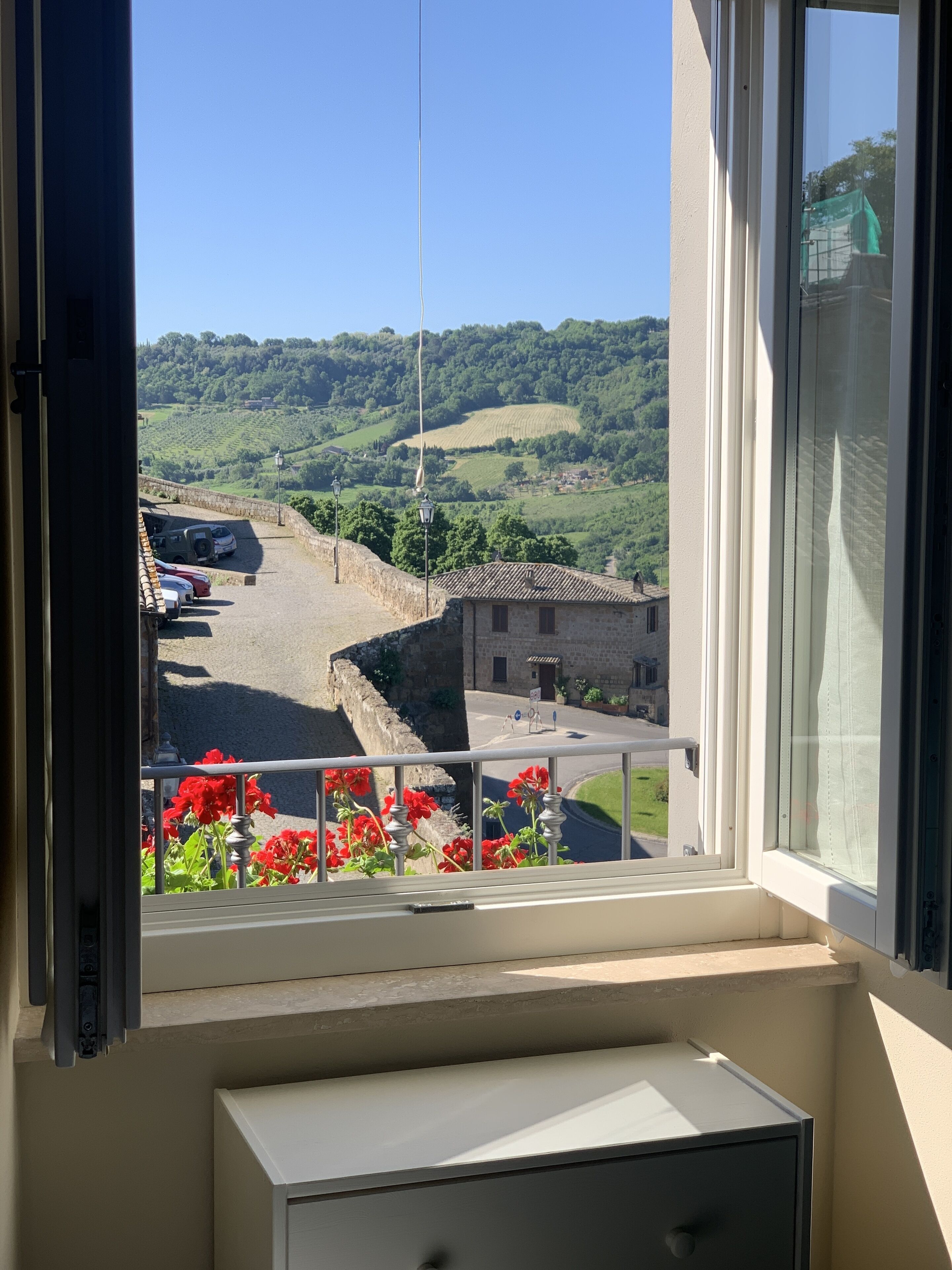 Una habitación con ventana que da a un estacionamiento y un paisaje verde.