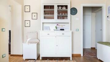 Ein Zimmer mit einem weißen Schrank, einem kleinen Nachttisch, einer Uhr und gerahmten Bildern an der Wand.