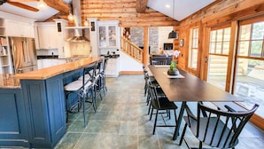 Cucina spaziosa con isola centrale, travi in legno e ampia zona pranzo con sedie.