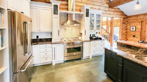 Una cucina moderna con mobili bianchi, un frigorifero in acciaio inossidabile, un piano cottura a gas e una grande isola con lavello.