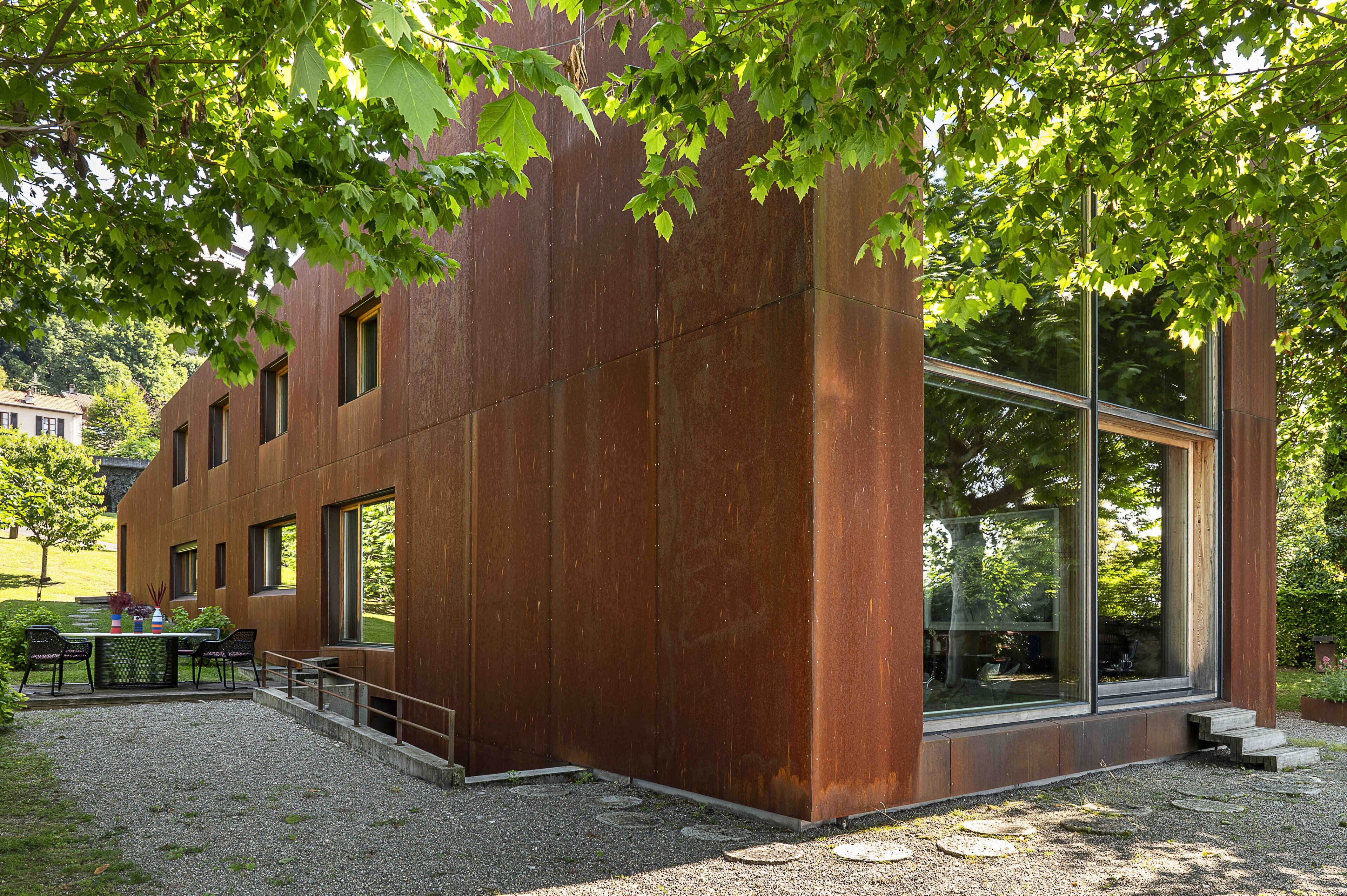 Un edificio moderno con amplias ventanas y un patio de grava con sillas.