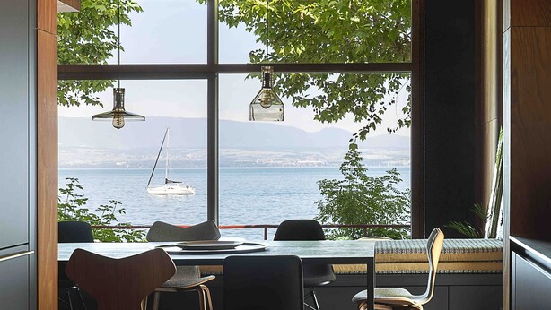 Un comedor moderno con vistas al mar y un velero.