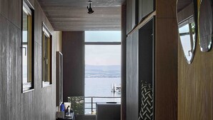 Un interior moderno con un largo pasillo, ventanas amplias y vista al agua.