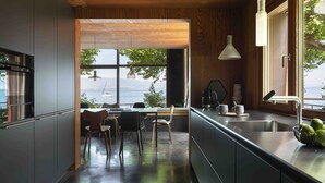 Una cocina moderna con vista al mar, un comedor con sillas y un ventanal grande.