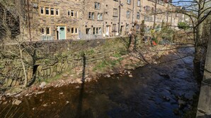 A stone building with multiple windows and a small stream running alongside. - Kingfisher Cottage (Holmfirth)
