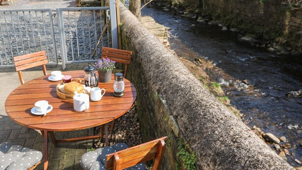 A wooden table with chairs, a kettle, a teapot, and a bowl of bread. - Kingfisher Cottage (Holmfirth)