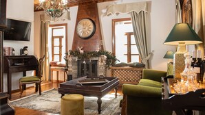 A cozy living room with a fireplace, wooden furniture, a chandelier, and a television. - Dandy Villas Nymfaio Snowfairy (Amyntaio)