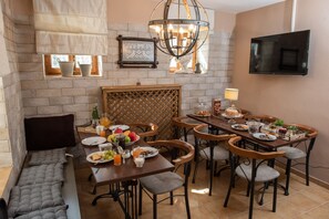 A dining area with a brick wall, a chandelier, and a flat-screen TV. - Dandy Villas Nymfaio Snowfairy (Amyntaio)