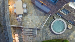 An aerial view of a patio area with stone flooring, outdoor furniture, a hot tub, and a small garden. - Dandy Villas Nymfaio Snowfairy (Amyntaio)