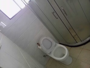 A bathroom with a toilet, a cabinet, and a visible pipe.