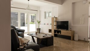 Een moderne woonkamer met een bank, salontafel, televisie en een eethoek.